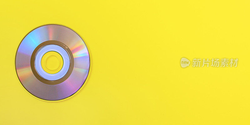自上而下的视图，小CD闪亮/彩虹的一面，在黄色的板上，文字的空间在右边。